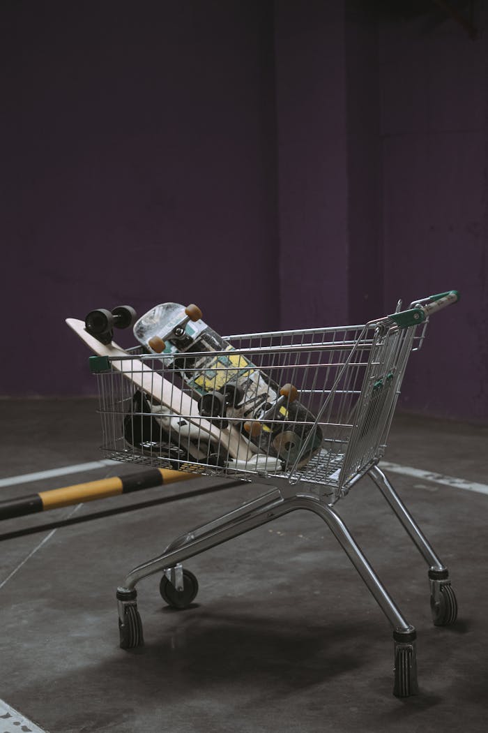 A shopping cart containing skateboards in an indoor parking area