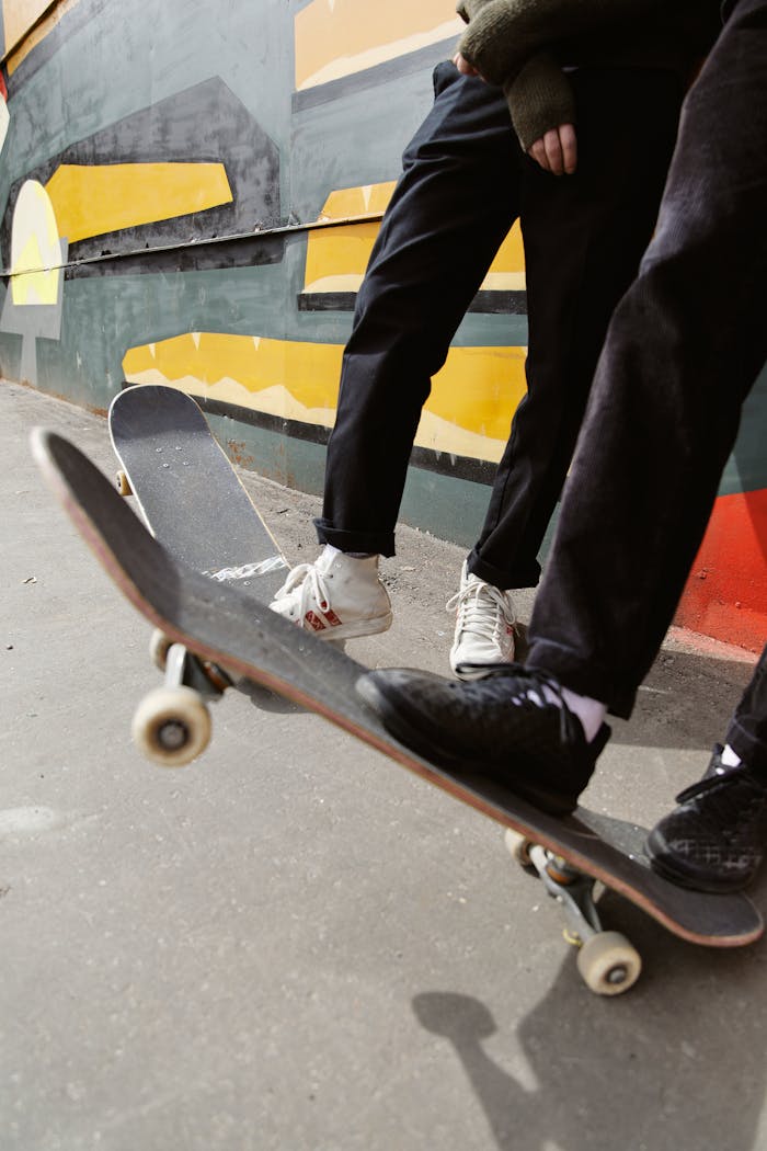 Two skateboarders performing tricks beside a vibrant graffiti mural.